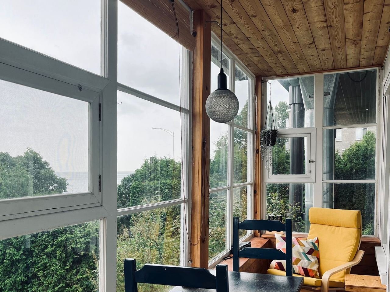 Yağmur ve rüzgara karşı kapatılmış, oturma alanı olarak kullanılan cam balkon uygulaması